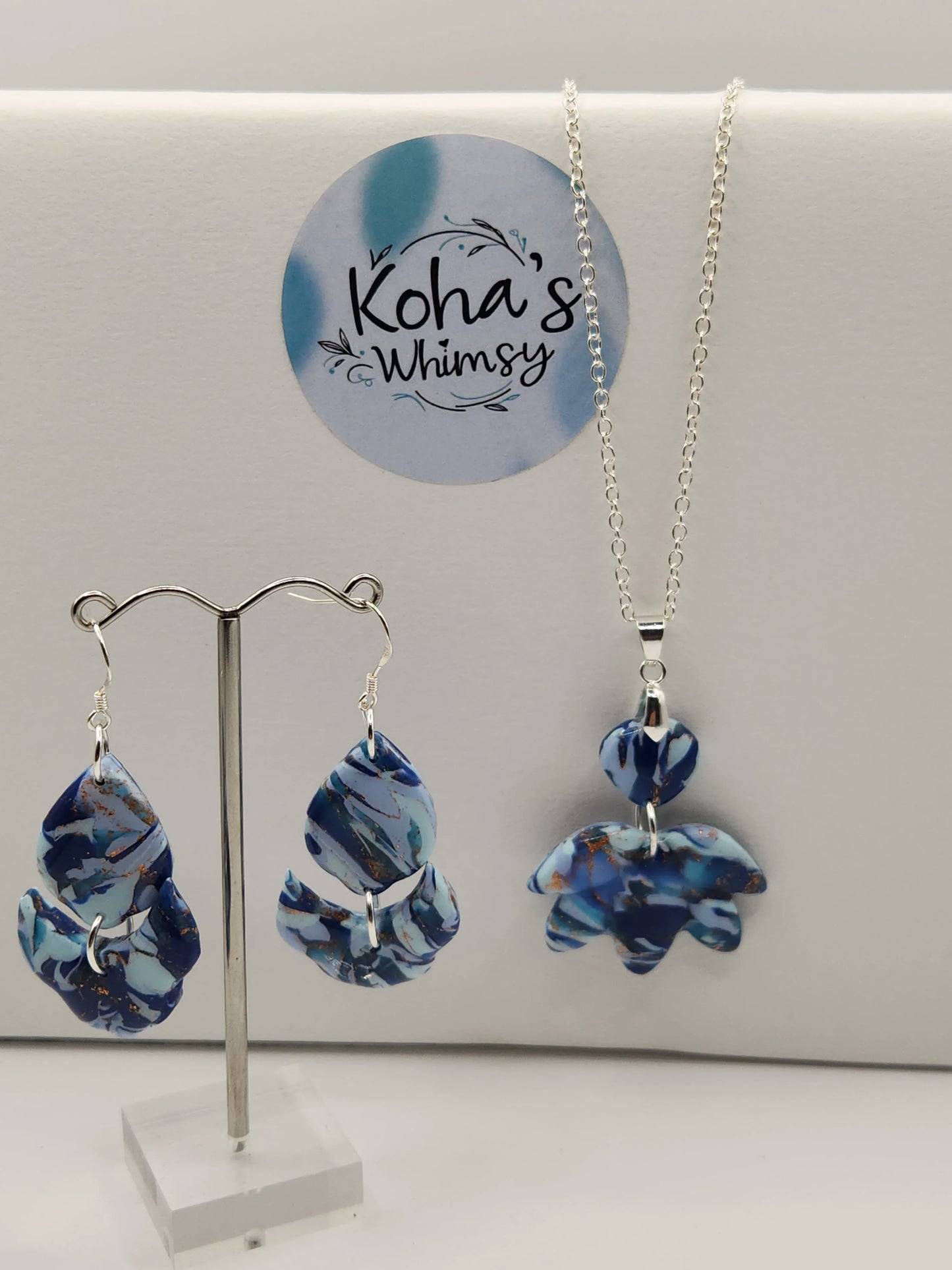 Blue and gold jewelry set by Koha's Whimsy, including earrings and pendant on a silver chain.