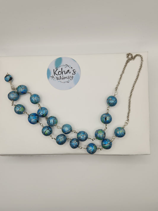 Close-up of unique watercolour necklace showing hand-painted azure blue beads and artistic detail