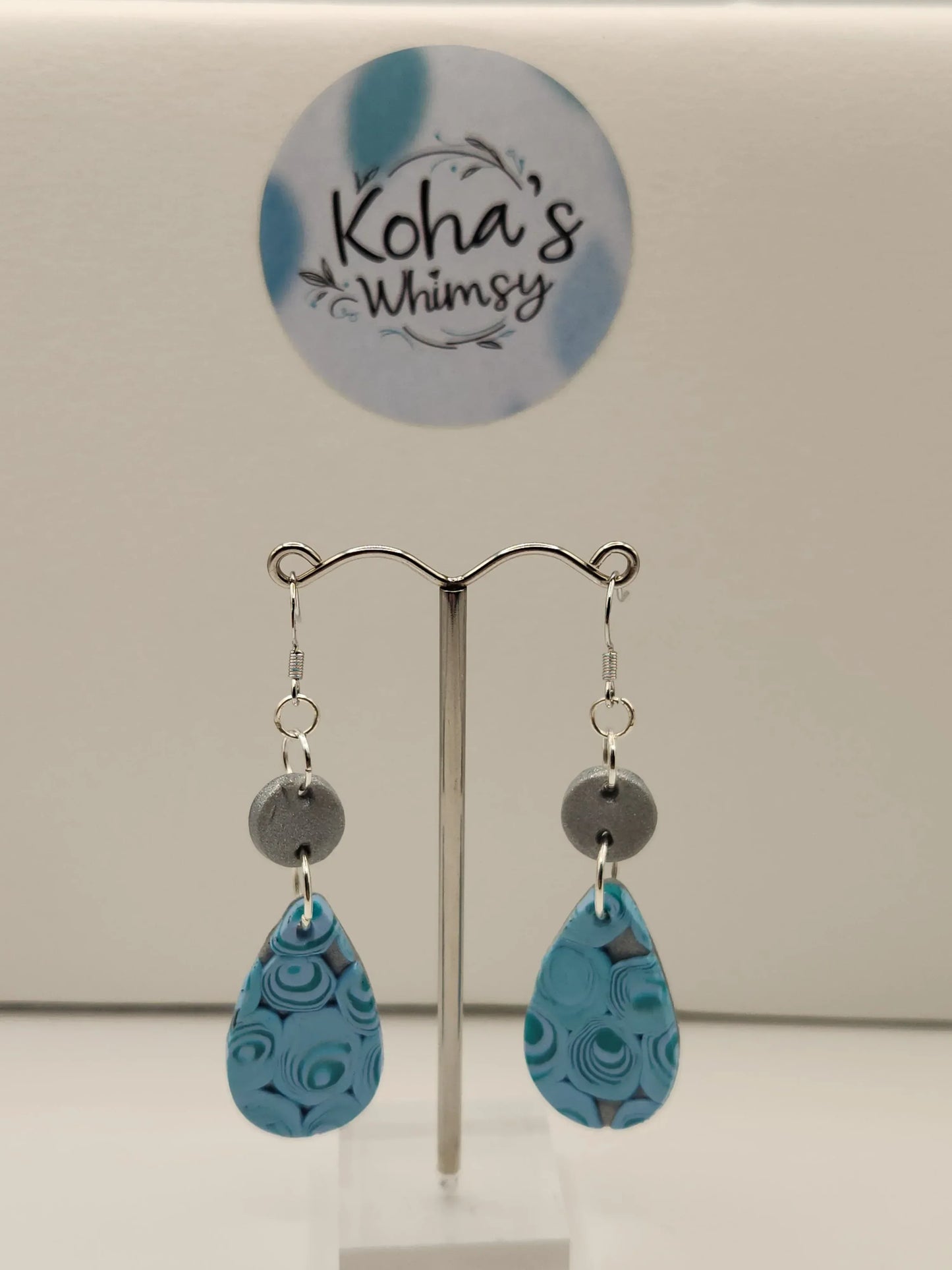 Teal swirl teardrop dangle earrings from Koha's Whimsy featuring a gray disc accent and silver hardware.