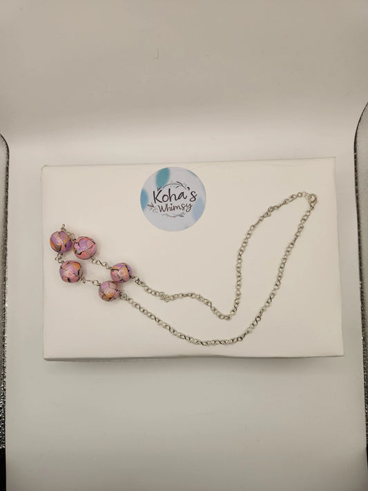 Pastel beaded necklace with a watercolour pattern by Koha's Whimsy, displayed on a white box with a silver chain.