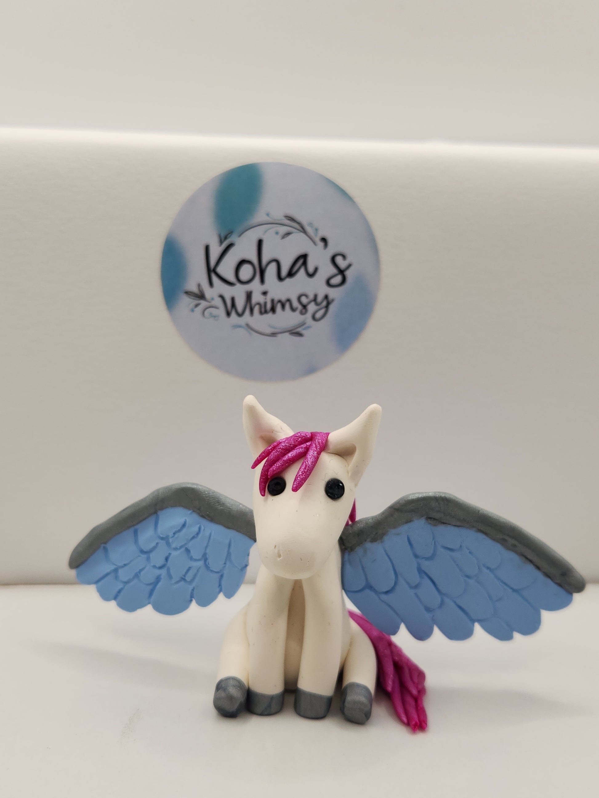 Faye the handmade polymer clay pegasus figurine with pink mane, white body, and colourful wings