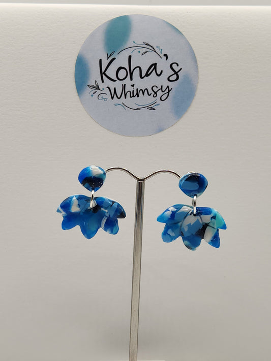 Close-up of navy burst lotus studs showing refined floral design with blue and white blend
