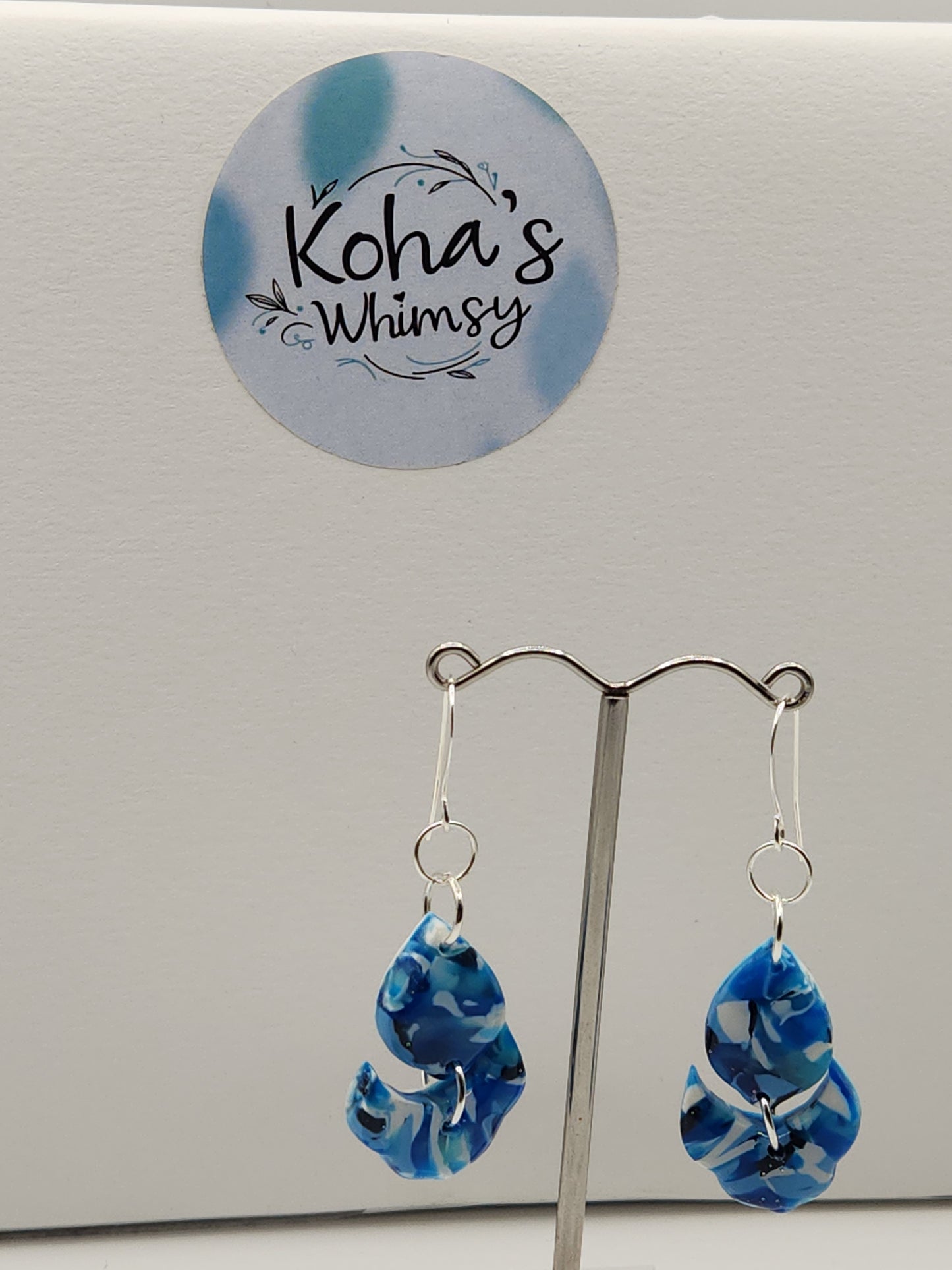 Close-up of navy burst earrings showing artful blend of blue and white with floral petal design
