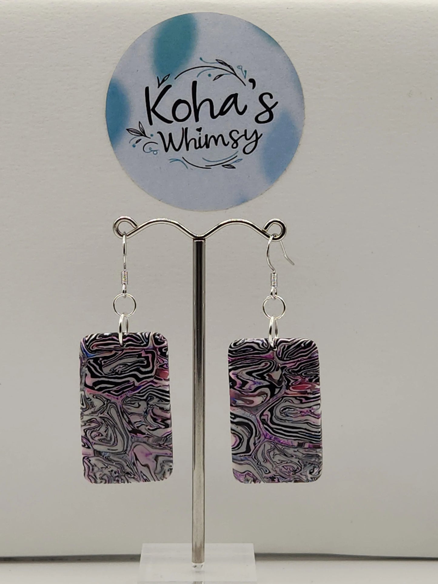 Rectangle dangle earrings with a marbled pattern by Koha's Whimsy, displayed on a silver-colored earring stand.