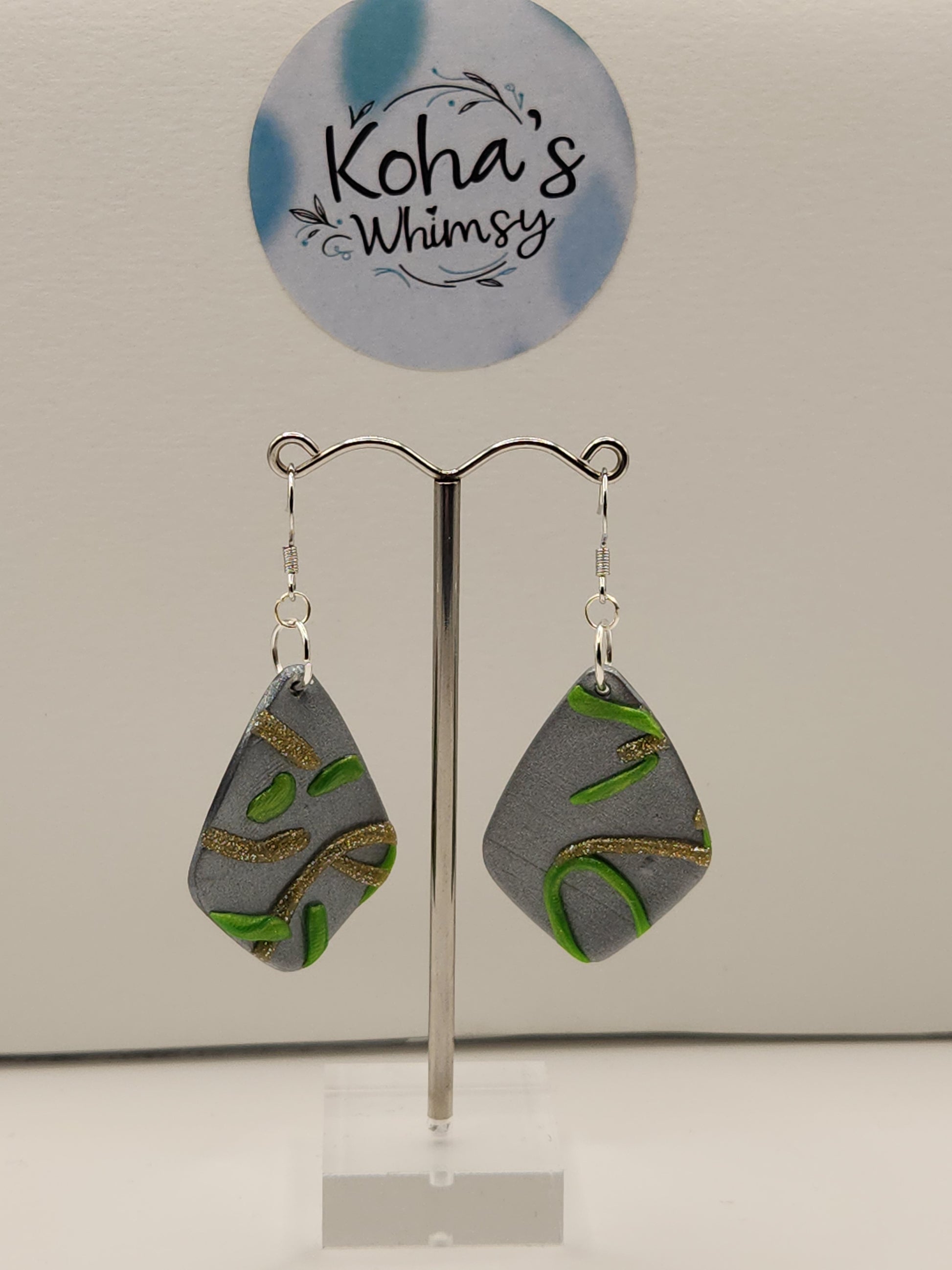 Close-up of large drop diamond dangle earrings showing abstract green and gold swirl pattern
