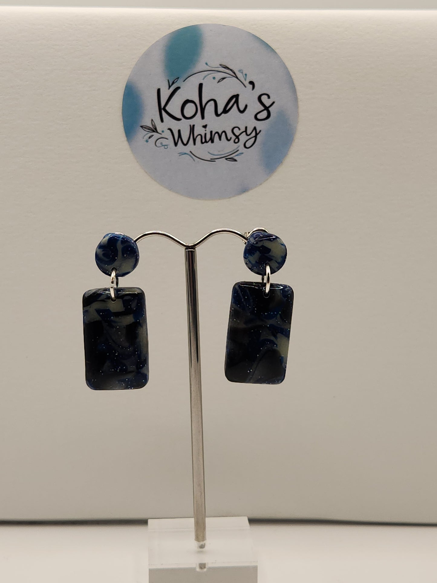 "Handmade polymer clay rectangle stud earrings with navy blue glitter and silver foil that glow in the dark"