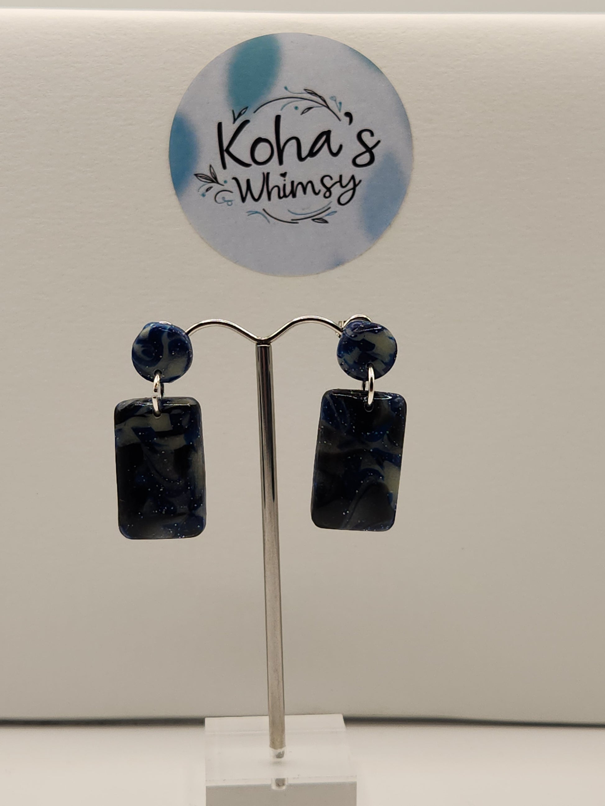 "Handmade polymer clay rectangle stud earrings with navy blue glitter and silver foil that glow in the dark"