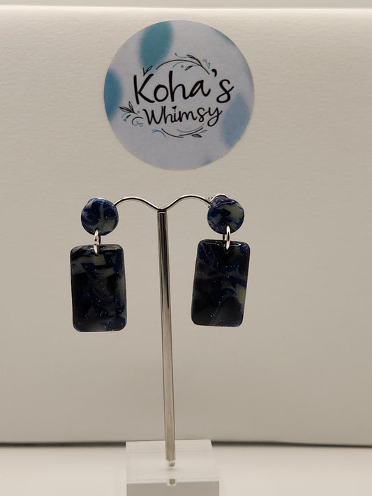 "Handmade polymer clay rectangle stud earrings with navy blue glitter and silver foil that glow in the dark"