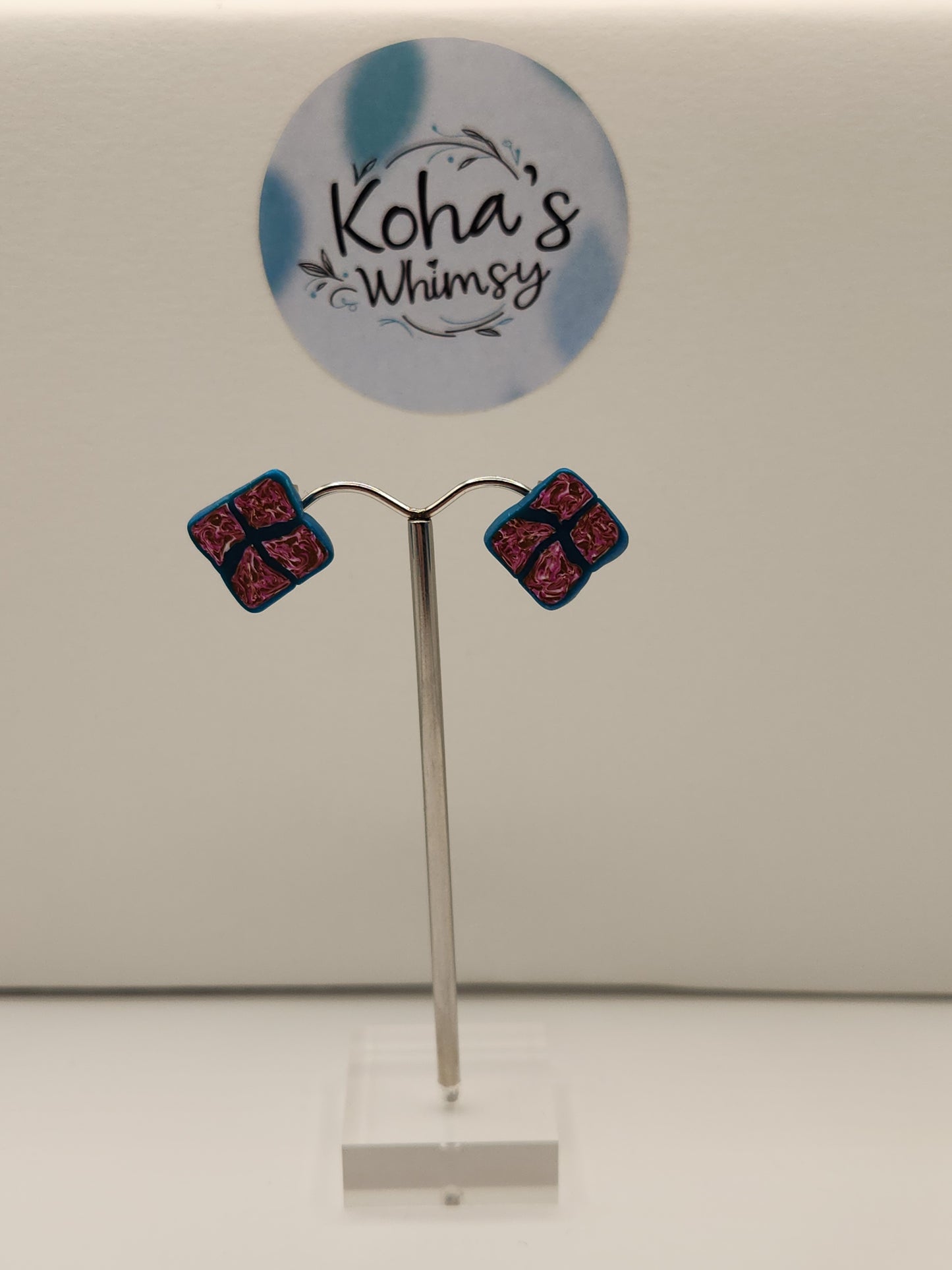 Handmade polymer clay diamond stud earrings with fuchsia, gold and white sections outlined in dark teal