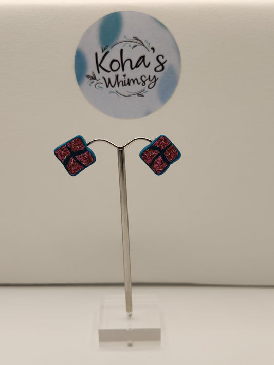 Handmade polymer clay diamond stud earrings with fuchsia, gold and white sections outlined in dark teal