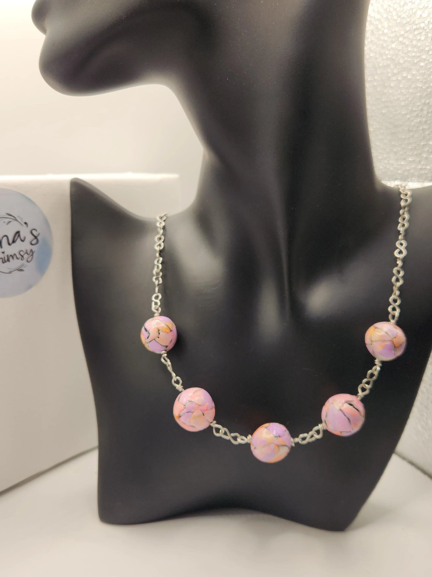 Pastel watercolour beaded necklace from Jenna's Whimsy, displayed on a black mannequin bust.
