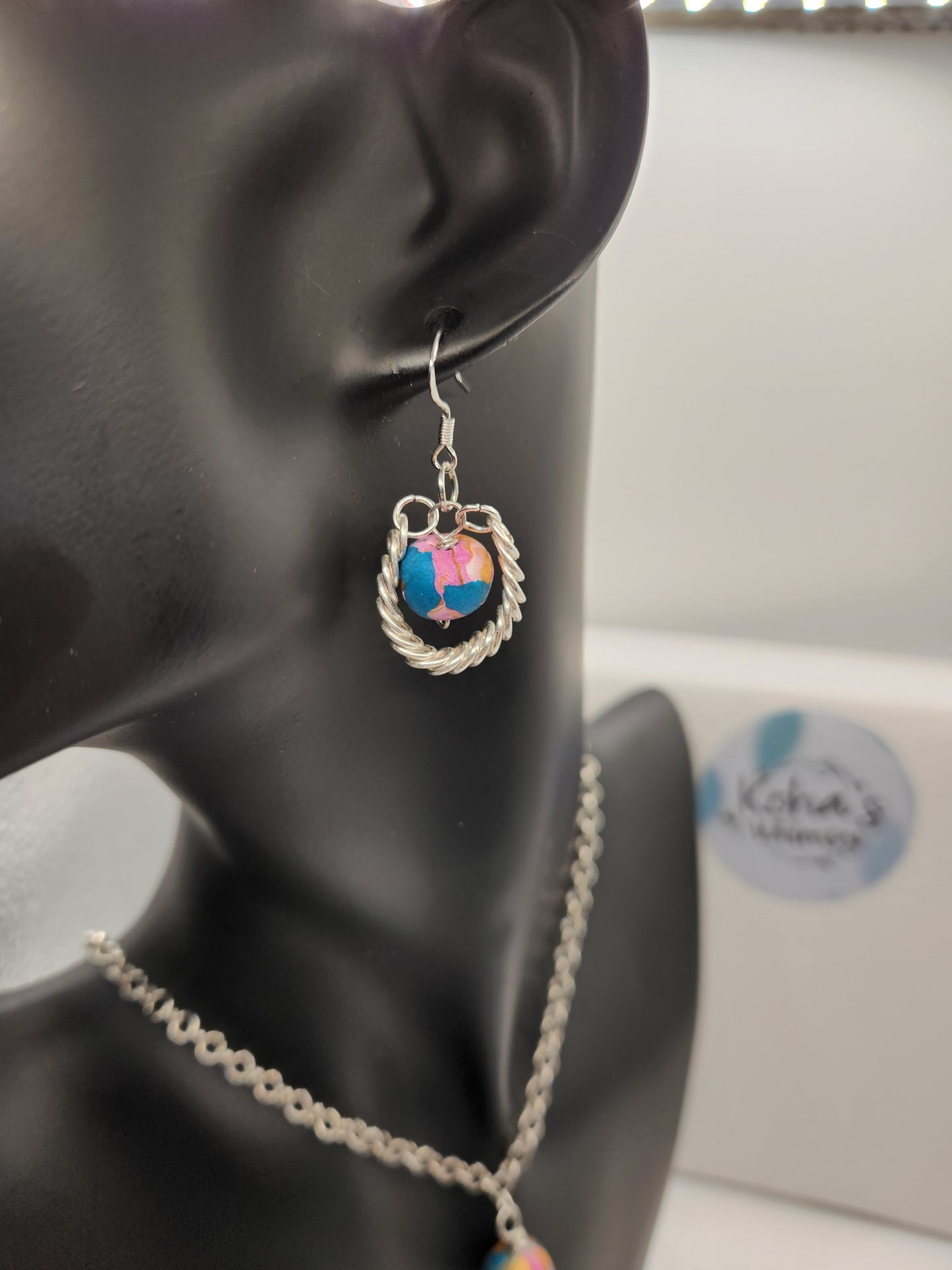 Handmade beaded earrings with coiled wire wrapping and pink, blue and gold polymer clay beads

