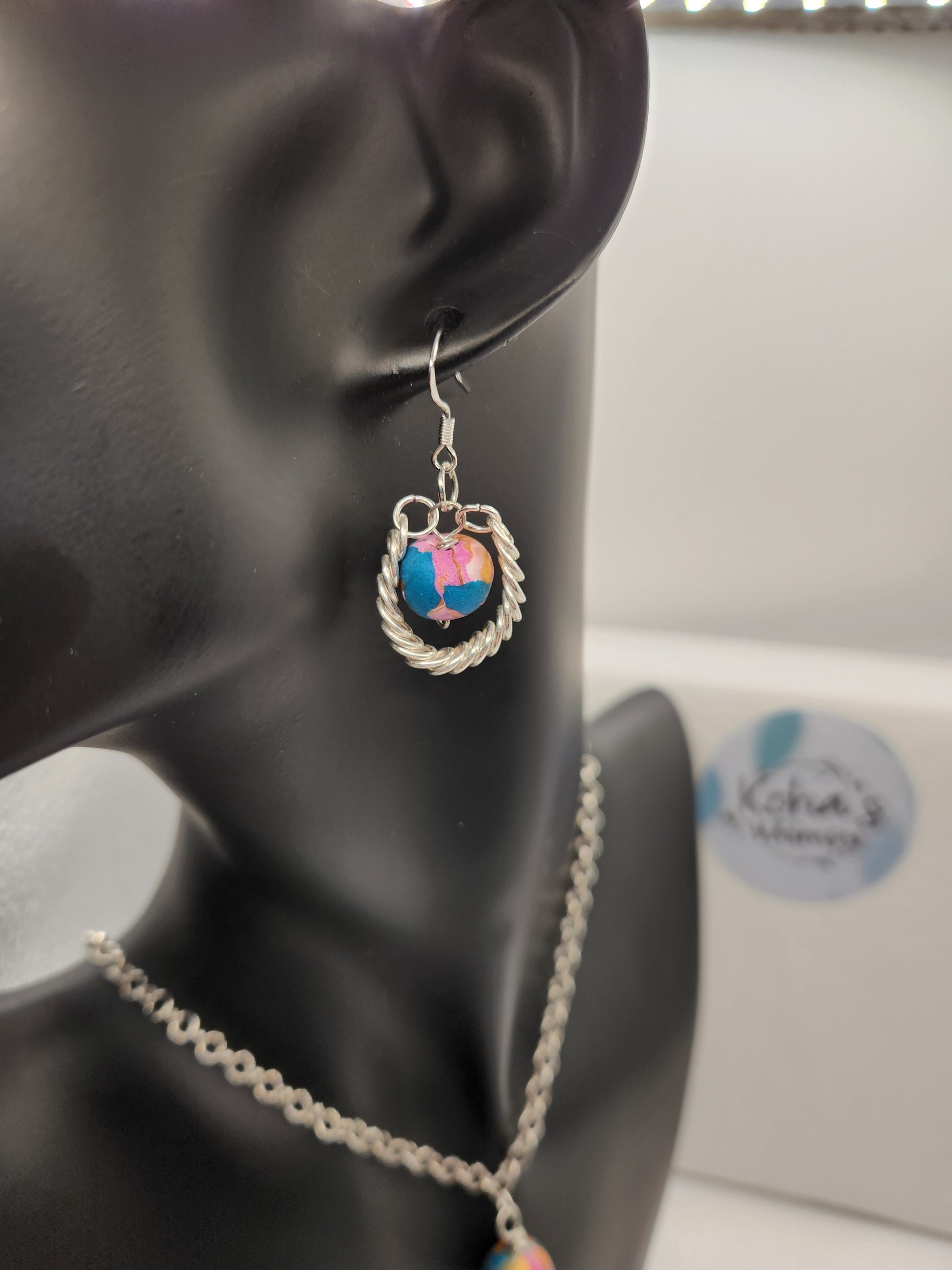 Handmade beaded earrings with coiled wire wrapping and pink, blue and gold polymer clay beads

