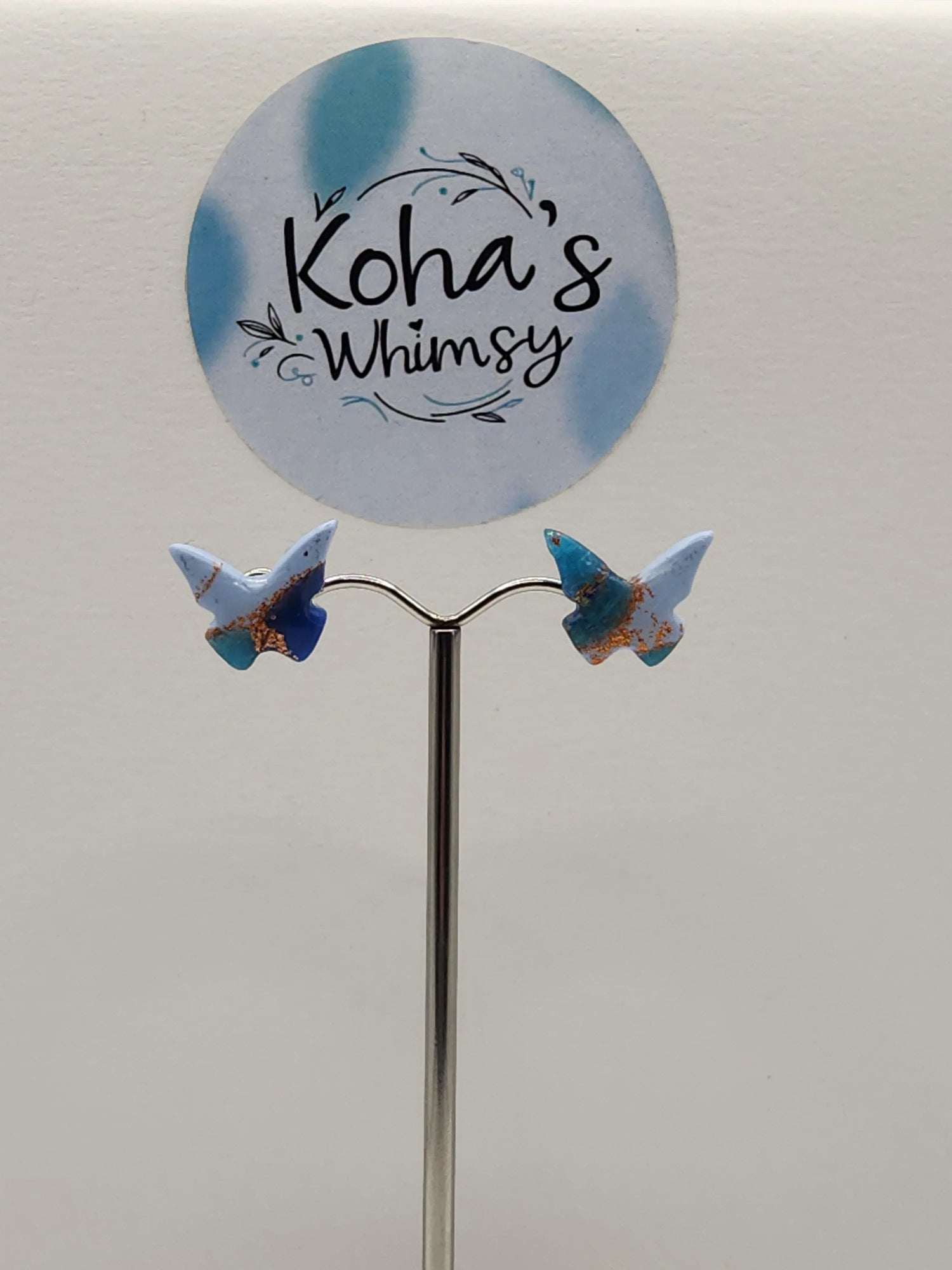 Blue butterfly stud earrings from Koha's Whimsy, showcasing marble and copper colored patterns.